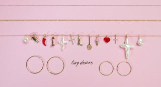 Jewelry charms on a string against a pink background