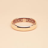Gold bangle with intricate design on a beige background